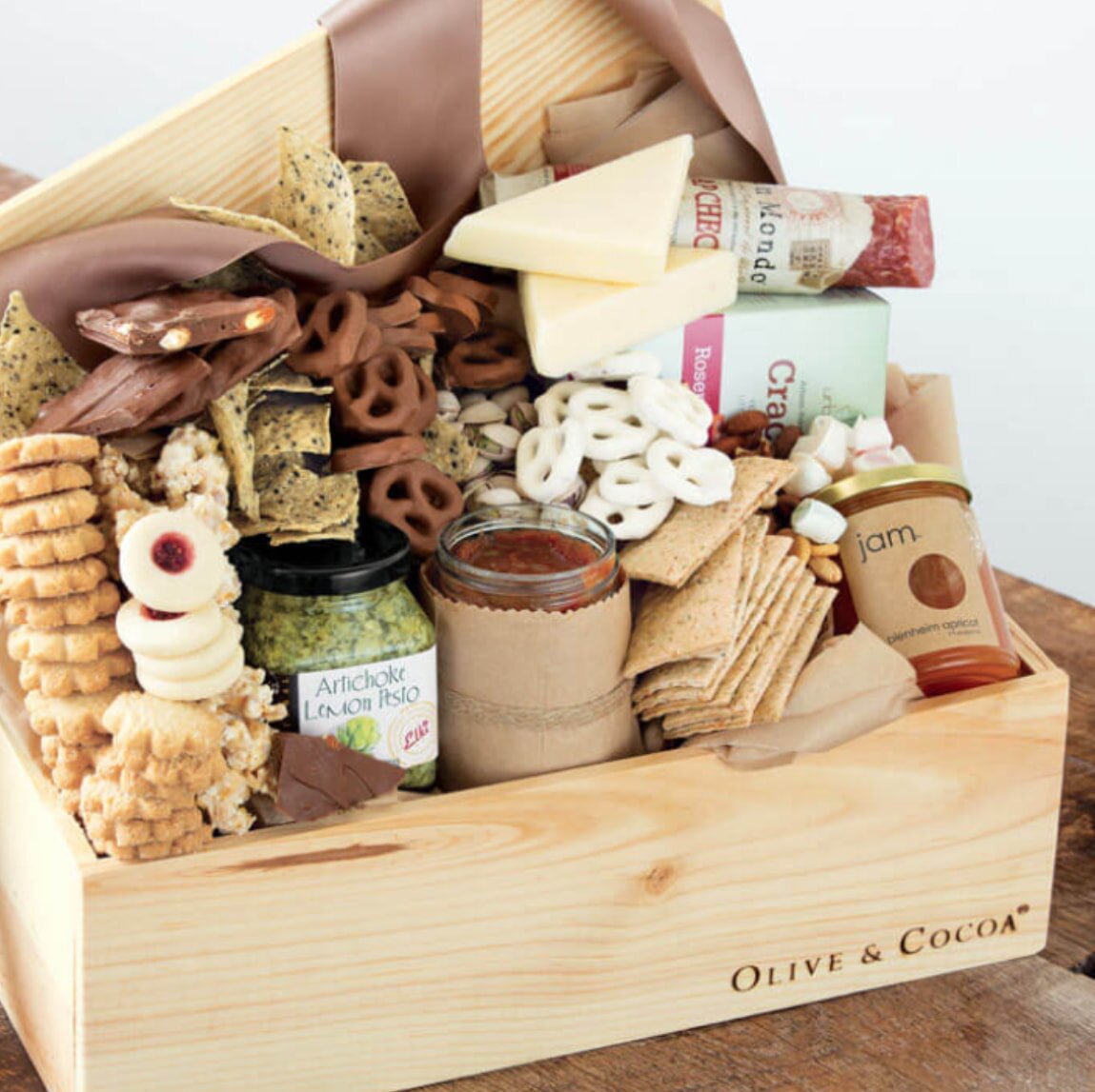 A wooden box overflowing with a variety of snacks and crackers arranged neatly inside.