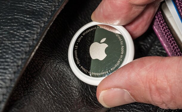A person holding a wallet featuring the Apple logo prominently displayed on its surface.