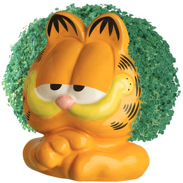 A topiary shaped like Garfield the cat, featuring green foliage and a playful expression, set in a garden landscape.