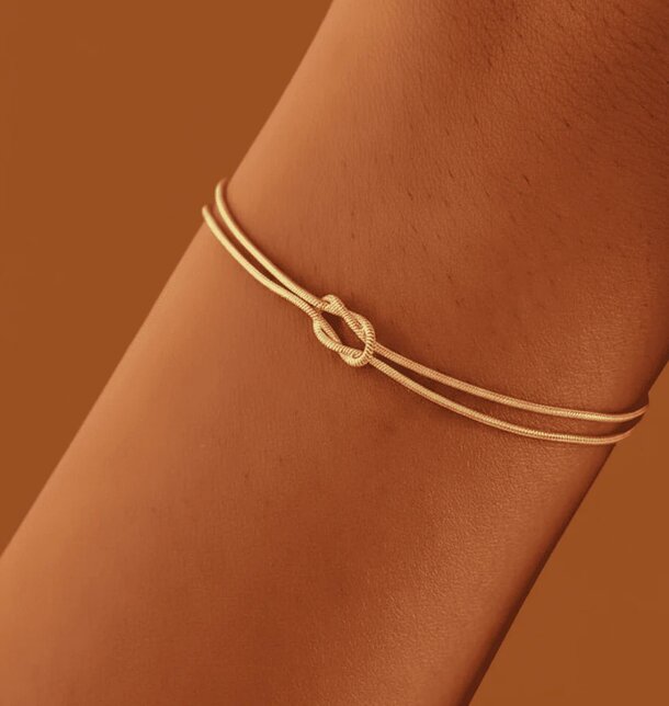 A woman sitting on a bench, wearing headphones, appears to be enjoying music or a podcast in a serene setting.