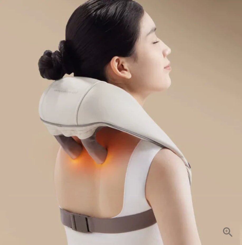 A woman enjoys a neck and shoulder massage using a wearable device with glowing heat nodes. She appears relaxed, eyes closed, in a serene setting.
