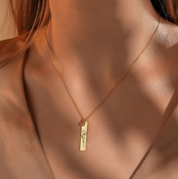 A memorial stone set in grass with leafy plants in the background. It features an image of a white dog named Penny and a heartfelt inscription below.