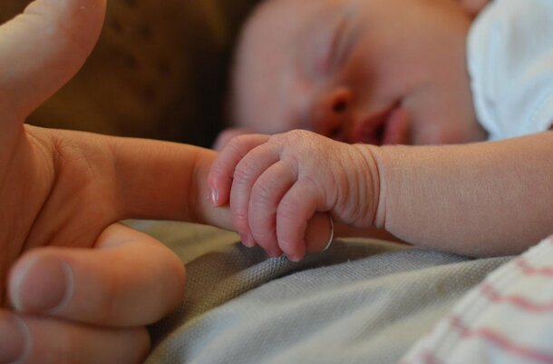 A peaceful baby sleeps gently on a person's hand, showcasing a tender moment of care and connection.