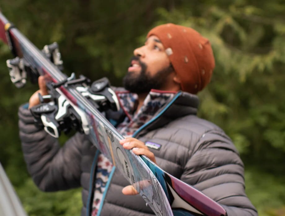 A man stands holding a pair of skis, ready for a day on the slopes.