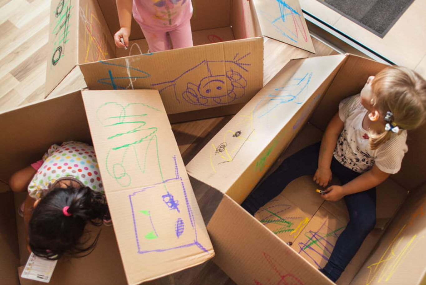 Two children joyfully playing with cardboard boxes, using their imagination to create a fun and engaging environment.