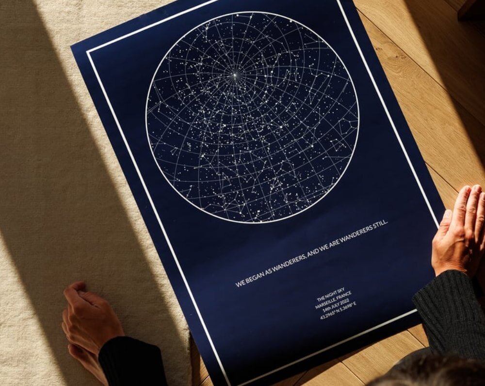 A person lies on the floor, studying a detailed map of the night sky, surrounded by stars and constellations.  