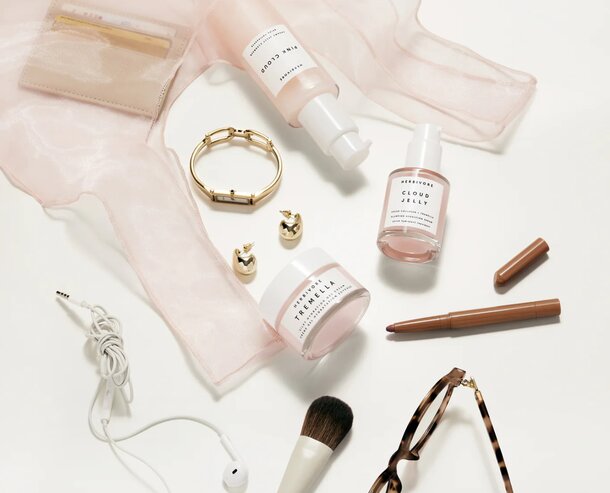 A pink bag filled with makeup, sunglasses, and various personal items arranged neatly inside.