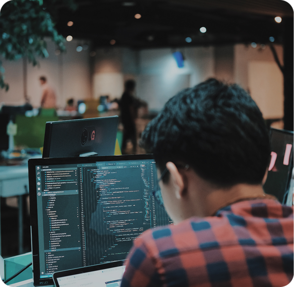 A person coding on a computer with a second monitor displaying code.
