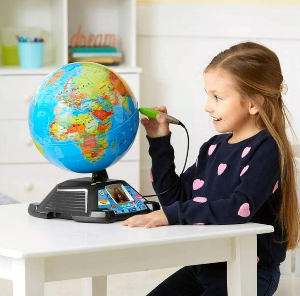 A young girl is seated at a table, examining a globe, showcasing her interest in geography.