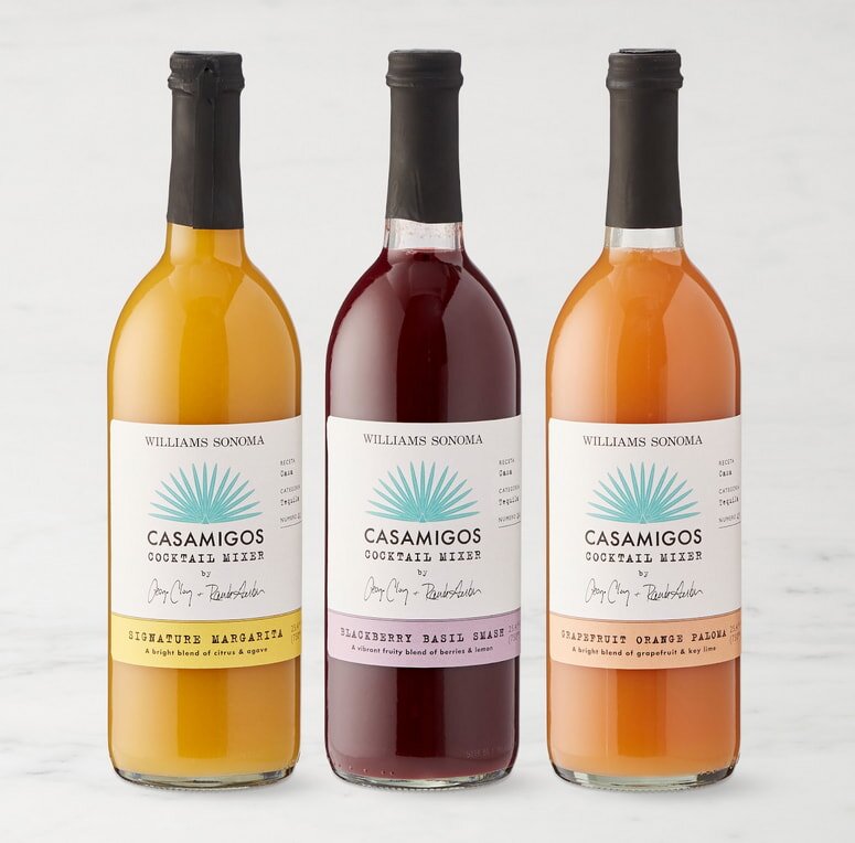 Three bottles of juice with colorful labels, showcasing different flavors, arranged on a wooden table.