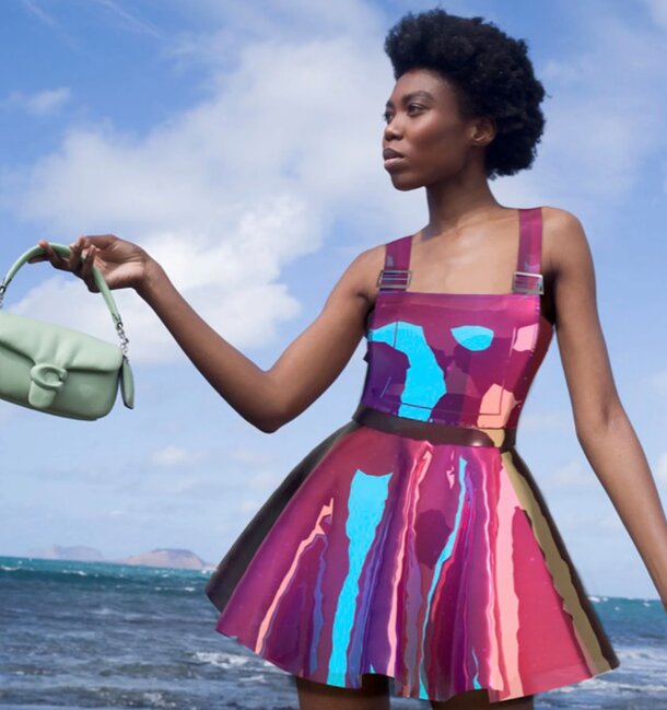 A woman in a vibrant dress holds a stylish purse, showcasing her colorful fashion sense.
