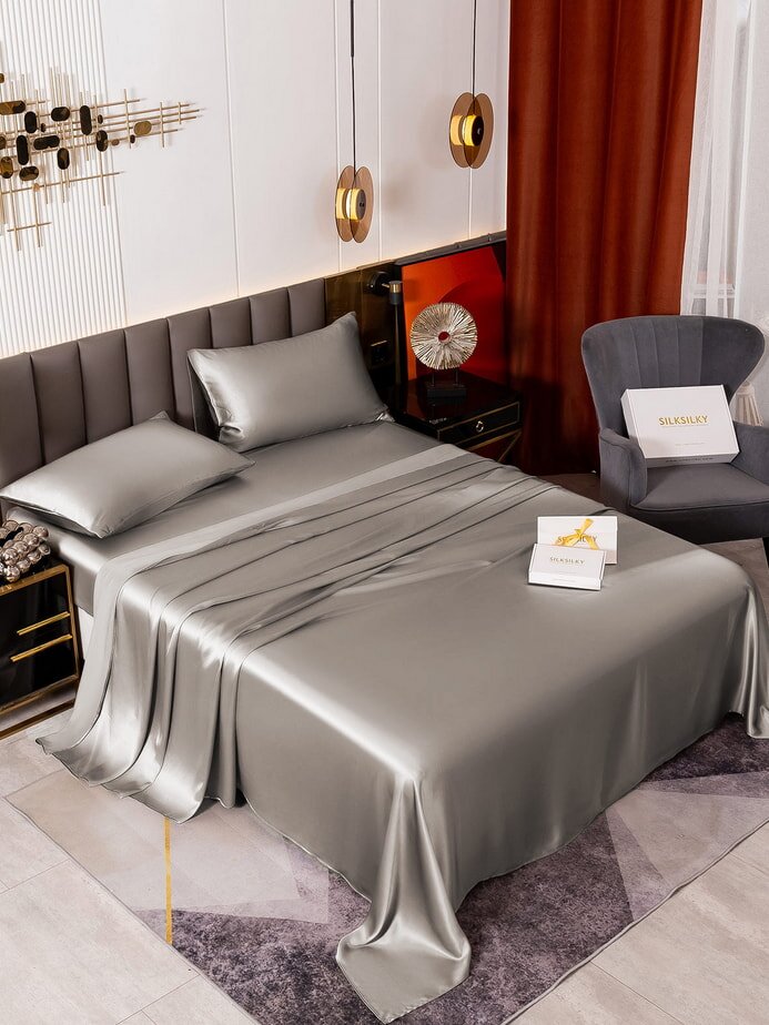 A neatly made bed featuring a silver sheet and matching pillows, creating a sleek and modern appearance.  