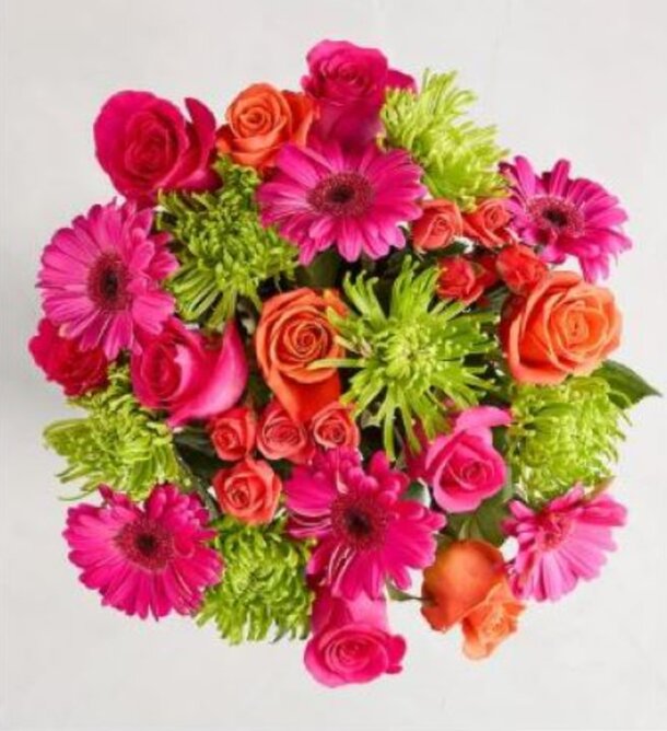 A vibrant bouquet featuring pink gerbera daisies, orange roses, and lime green chrysanthemums, arranged in a cheerful, lively composition.