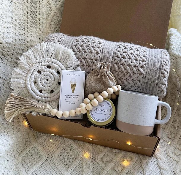 A cozy box containing a blanket, a mug, and various other comforting items for relaxation.
