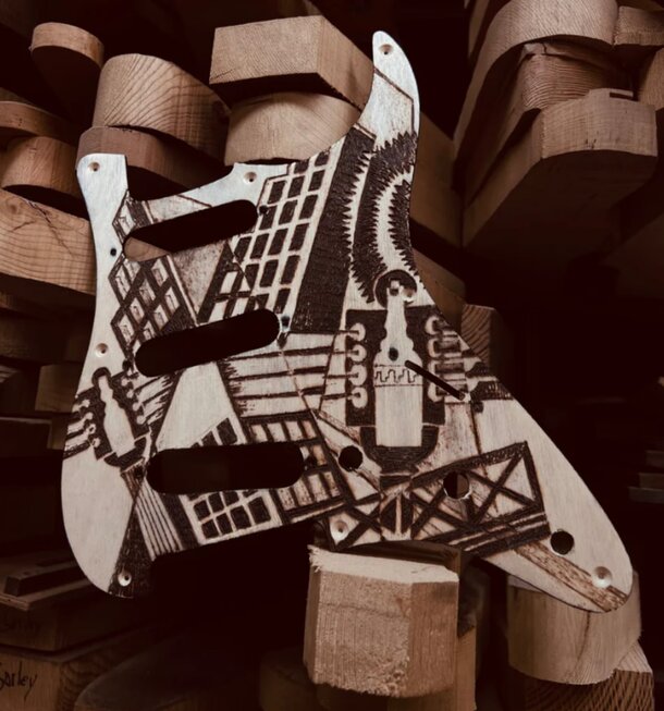 A decorated guitar rests atop a stack of wooden logs, showcasing its unique design against a natural backdrop.
