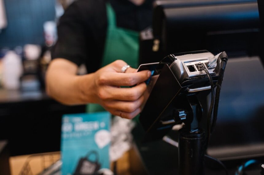 A person is using a credit card to complete a payment at a checkout counter.