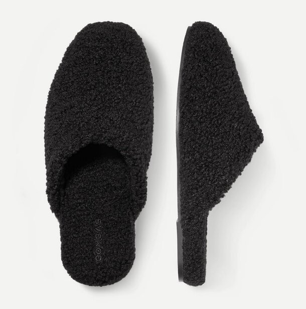 A pair of black slippers resting on a clean white surface.