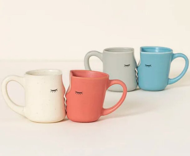 Three coffee mugs with cheerful faces, each displaying a unique expression, arranged side by side on a table.