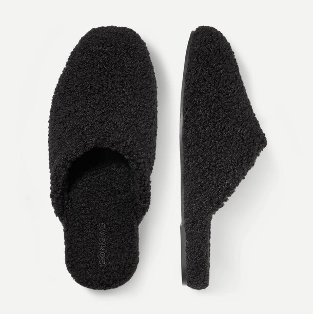 A pair of black slippers resting on a clean white surface.