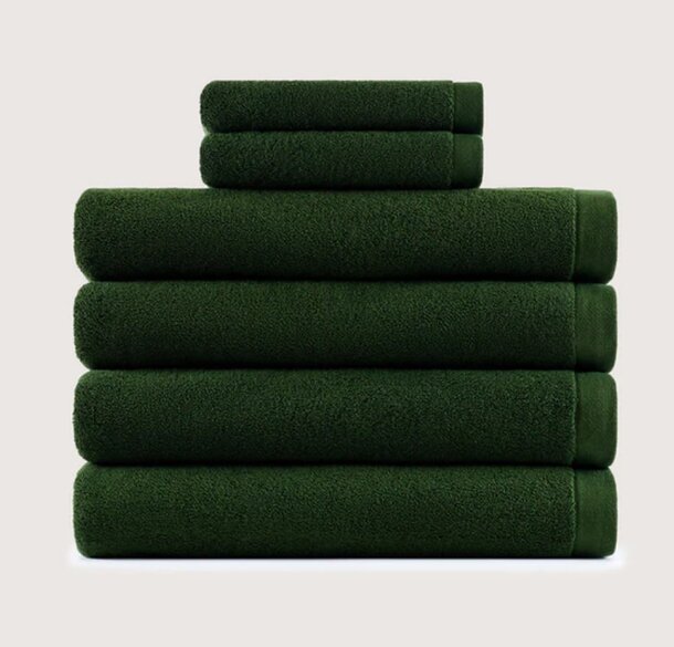 A neatly stacked set of six plush, dark green towels against a plain light background, conveying a sense of luxury, softness, and organization.