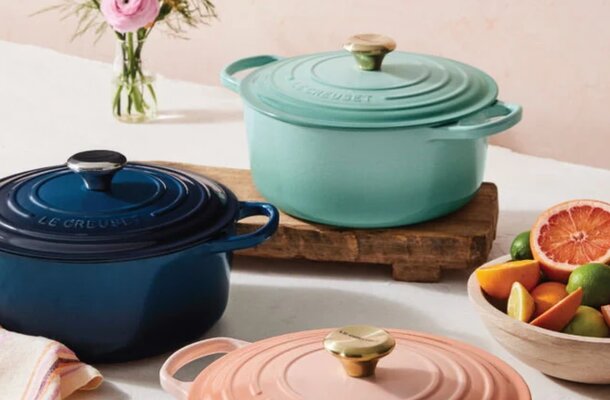 A collection of colorful Le Creuset Dutch ovens arranged on a wooden surface, showcasing their iconic design and vibrant hues.