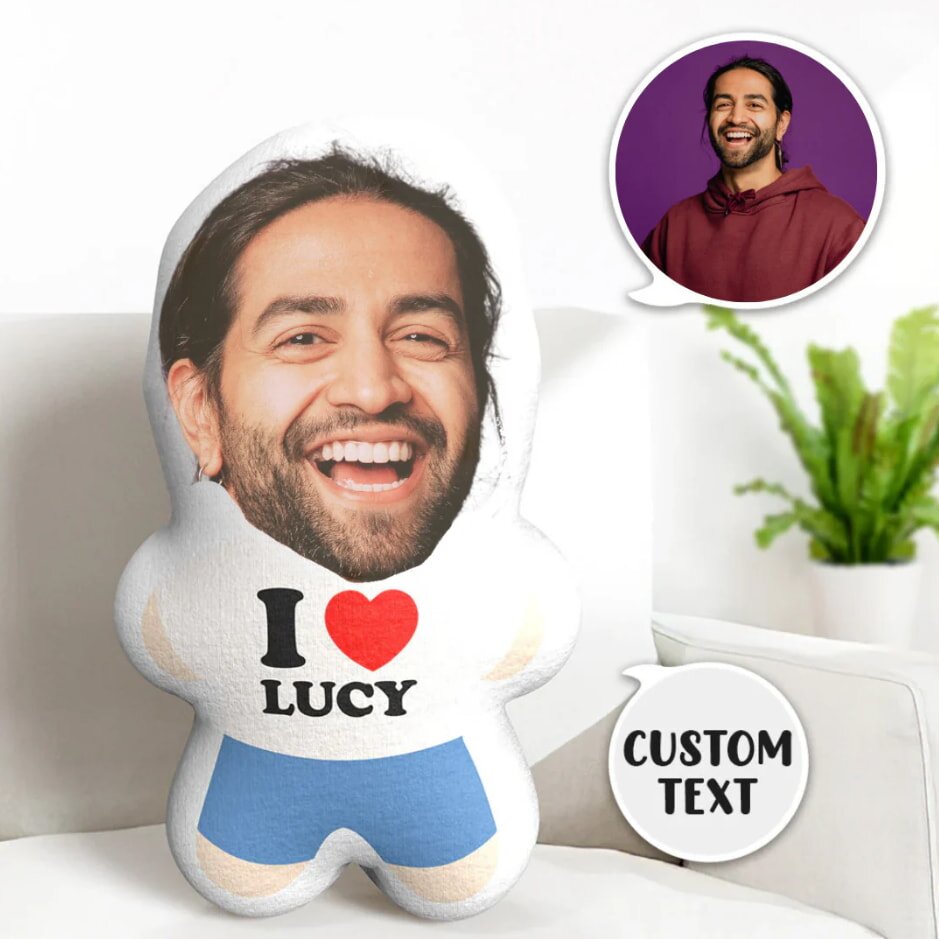 A pillow with a man's smiling face and "I ♥ Lucy" on the body. Inset photo shows the same man on purple background. Green plant in the background.