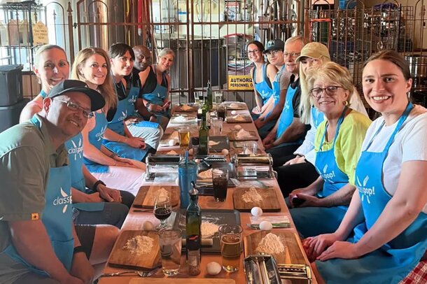 A group of people enjoying drinks and conversation at a table inside a brewery.