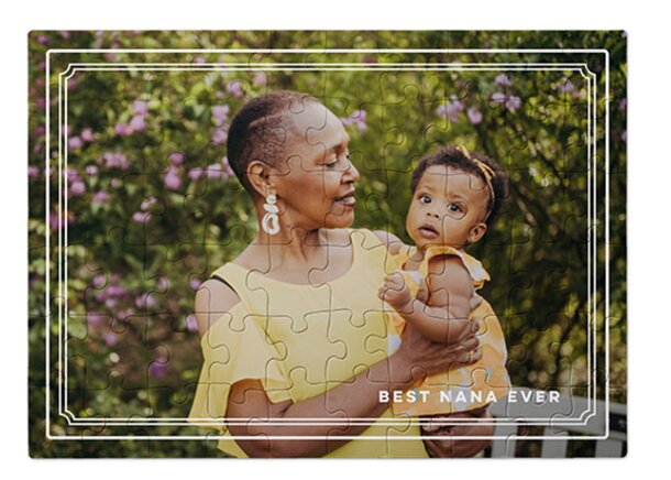 A mother and daughter work together on a jigsaw puzzle inside a decorative frame, smiling and enjoying their time.