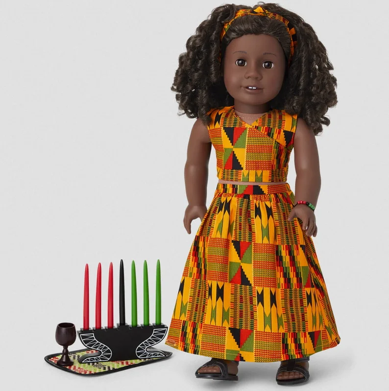 A doll dressed in traditional African attire stands beside lit candles, creating a warm and cultural ambiance.