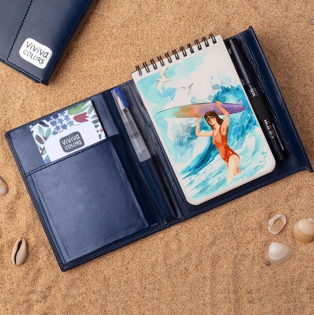 A5 notebook with a decorative cover placed next to a sleek pen on a flat surface.