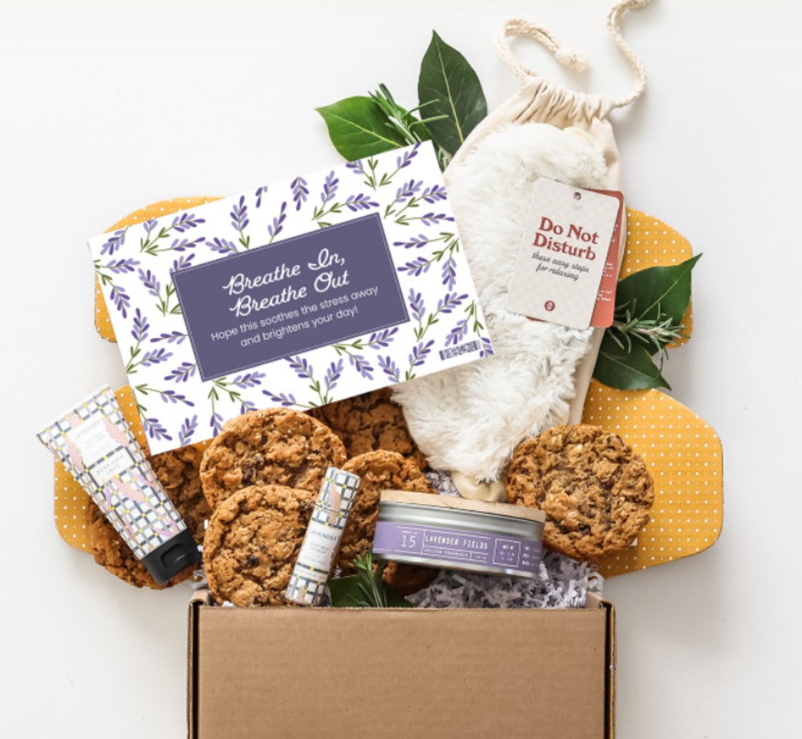 A lavender box filled with assorted cookies and a greeting card on top.