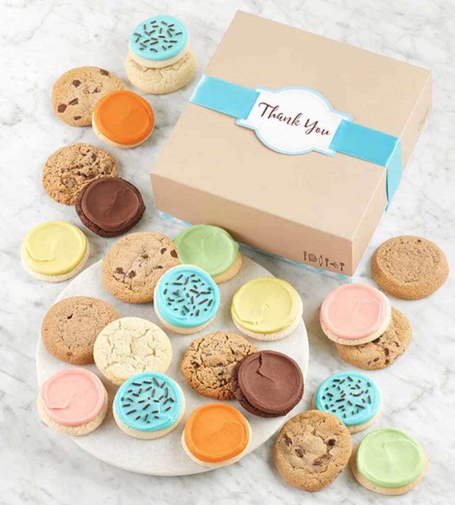 Assorted cookies with colorful frosting and chocolate chips are displayed on a marble surface. A box labeled "Thank You" sits nearby, creating a cheerful tone.