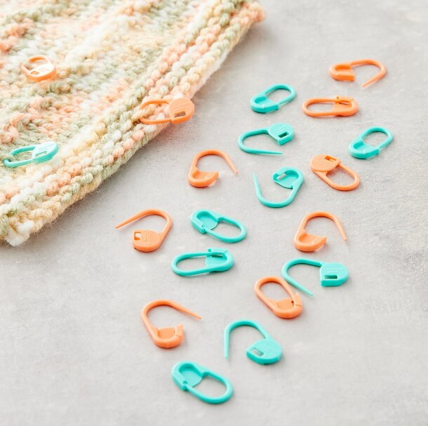 A knitted hat featuring orange and green plastic hooks, showcasing a unique and colorful design.