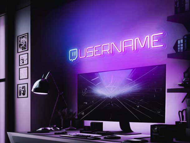 A computer screen displaying a vibrant neon sign, illuminating the workspace with colorful light.