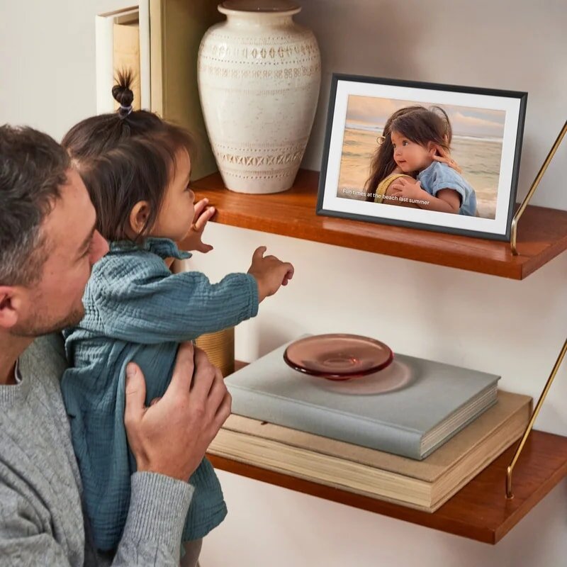Aura Carver Mat digital photo frame with a white mat displaying a family photo on a side table.