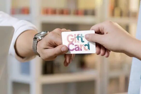 A man presents a gift card to another individual, showcasing a moment of generosity.