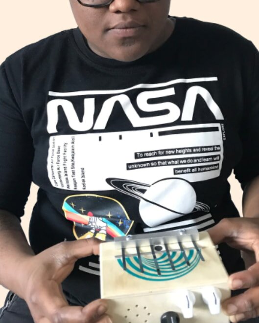 A person wearing a NASA shirt with a space theme holds a small kalimba. The tone is curious and creative, highlighting a blend of science and art.