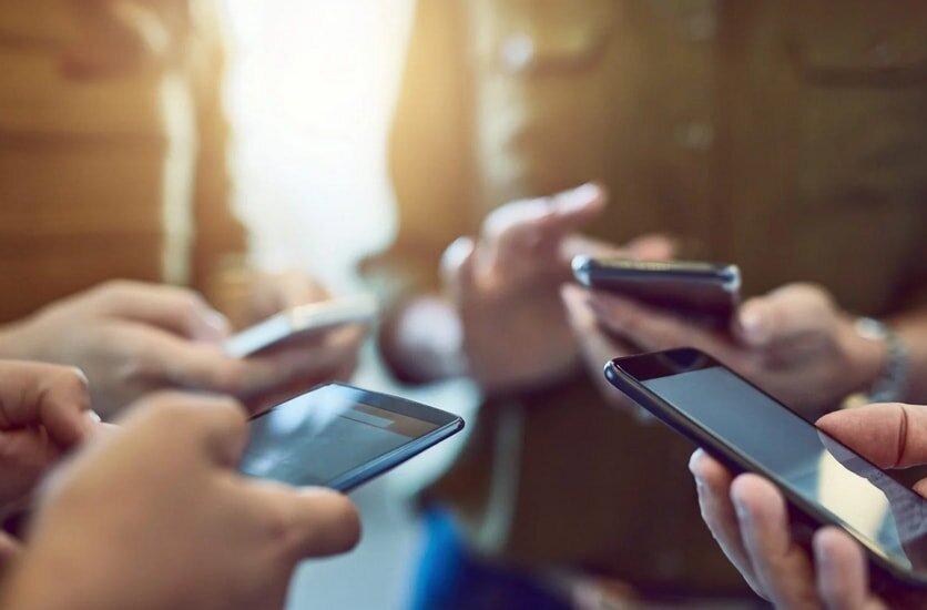 A group of people holding their cell phones, engaged in conversation or looking at their screens. 
