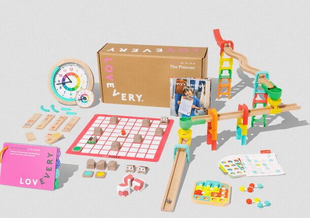 A colorful box filled with various toys and a book resting on top.