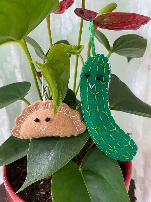 Two stuffed animals perched on a potted plant, surrounded by green leaves and soft sunlight.