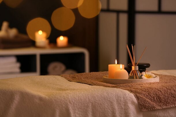 A massage table set with neatly arranged towels and lit candles, creating a calming and serene atmosphere.