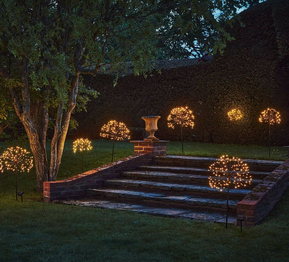 Solar-Powered Garden Lighting - A beautifully lit garden with twinkling lights strung among vibrant trees, creating a magical ambiance.