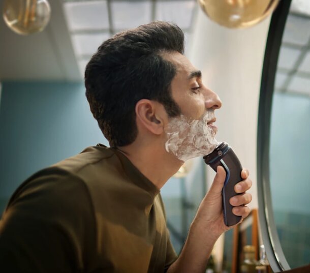 A man carefully shaving his face with a razor, focusing on achieving a clean and smooth appearance.