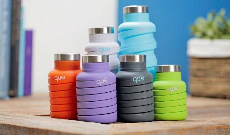 Collapsible water bottles in orange, purple, gray, green, and blue on a wooden table