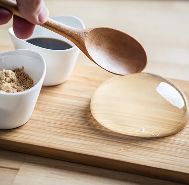 A person holds a spoon above a bowl filled with a liquid, preparing to serve or taste the contents.