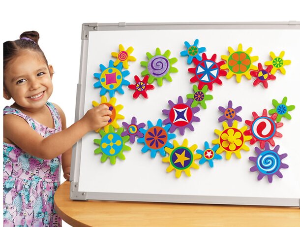 A young girl holds a magnet board decorated with vibrant, colorful flowers, showcasing her creativity and playfulness.