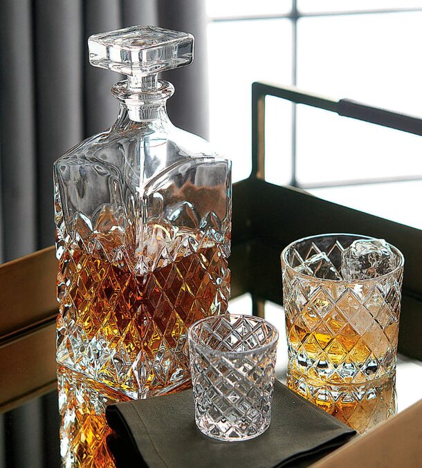 A glass decanter with two matching glasses elegantly arranged on a decorative tray.