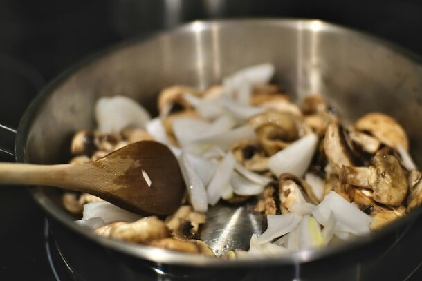 A frying pan filled with sautéed mushrooms and onions, showcasing a golden-brown color and a savory aroma.