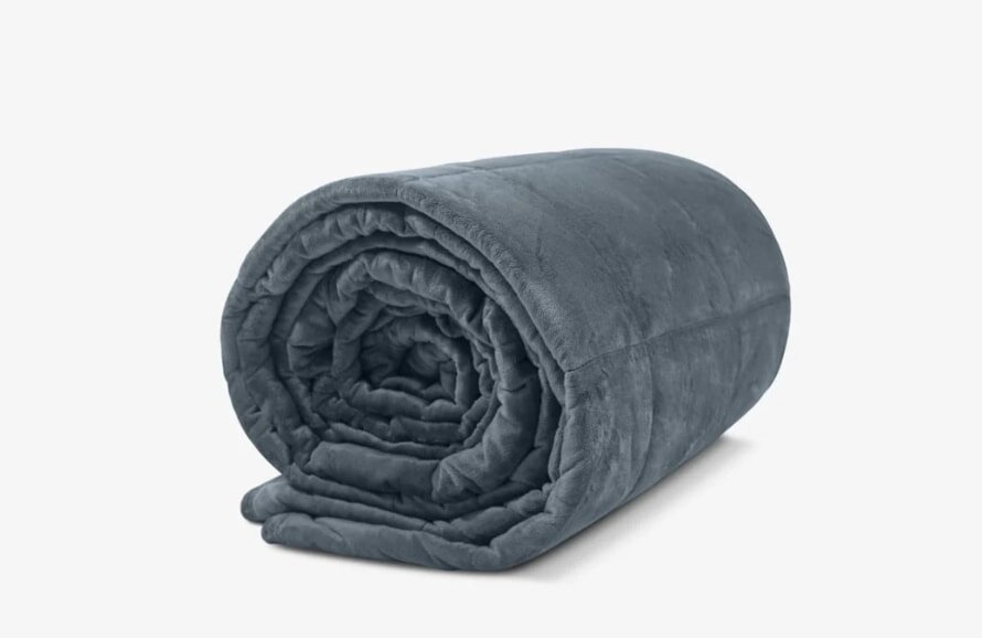A soft, dark gray weighted blanket is neatly rolled up on a plain white background, conveying a sense of warmth and comfort.
