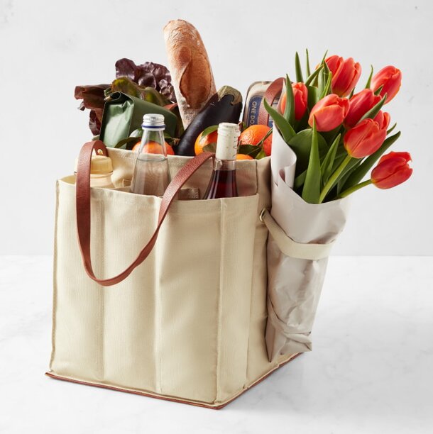 A grocery bag filled with colorful flowers and various food items, showcasing a vibrant and fresh assortment.